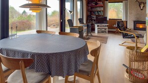 A dining area with a round table, chairs, and a bookshelf in the background. - 3 bedroom stunning home in Knebel (Knebel)