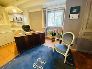 Ein Zimmer mit Schreibtisch, Stuhl und einem großen Fenster.