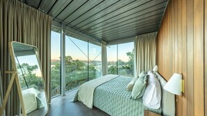 Une chambre avec un grand lit, un miroir et une vue sur l’extérieur.