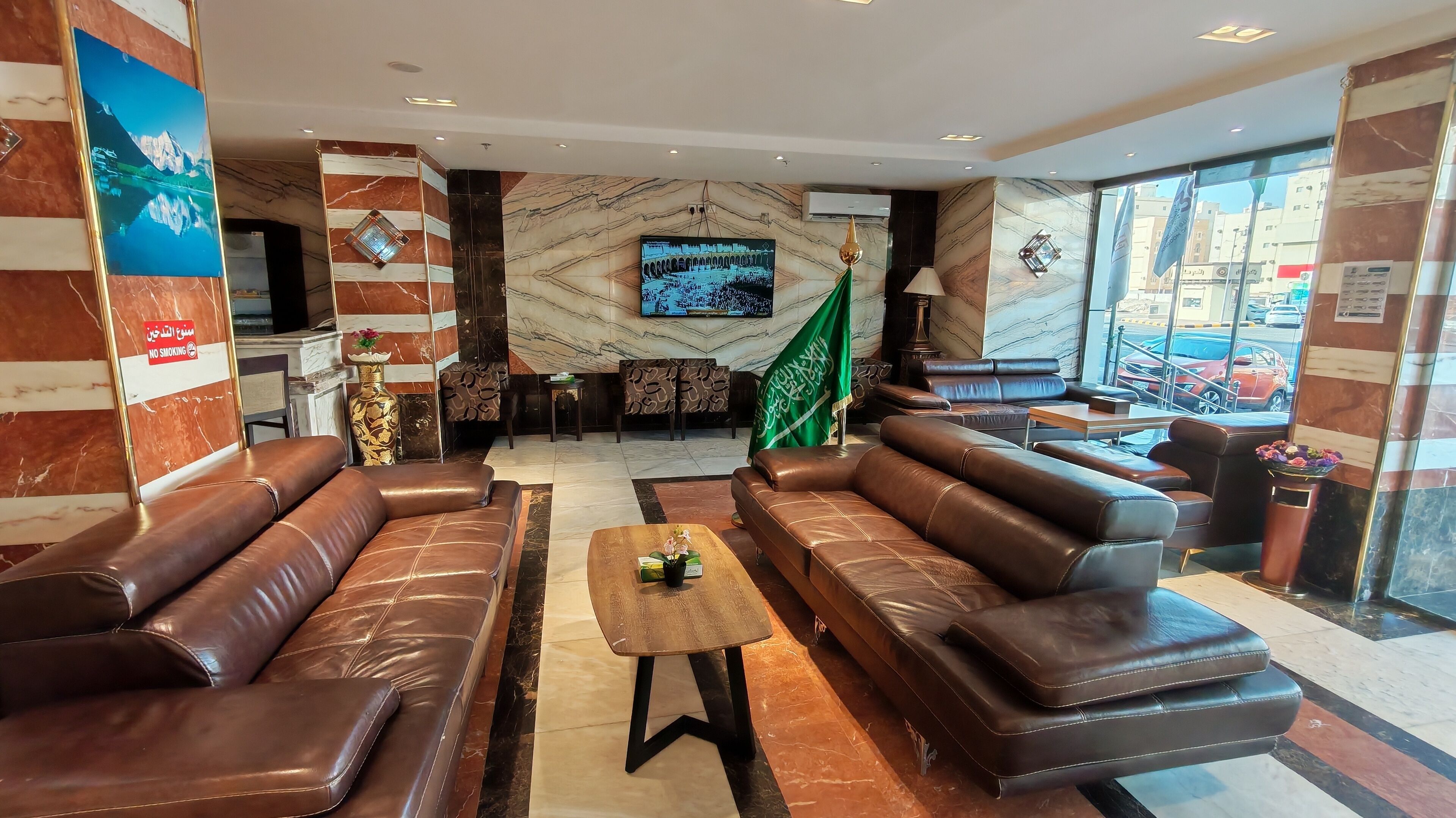 A lobby with leather sofas, a coffee table, a TV, and a flag.