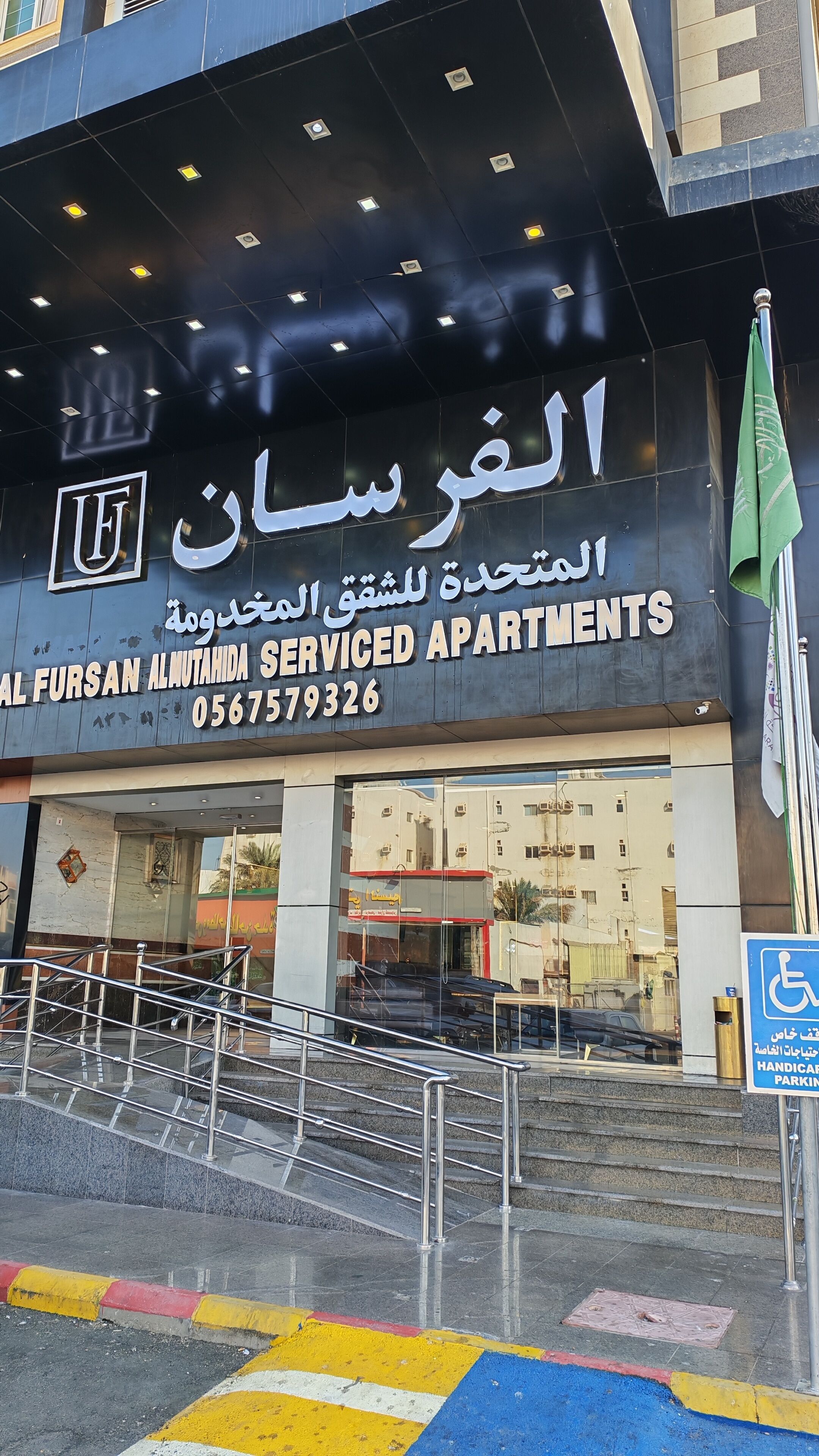 Un edificio con un cartello per 'Al Fursan Almutahida Serviced Apartments' e un segnale che indica parcheggio accessibile per disabili.