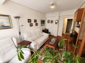 Ein Wohnzimmer mit Sofa, Couchtisch, Lampe und Bücherregal.