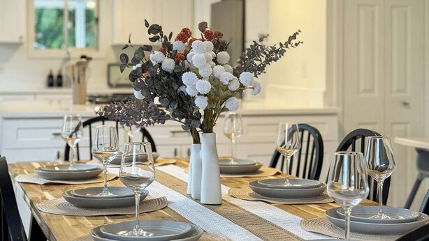 A dining table set with plates, glasses, and a centerpiece of flowers.