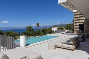 A pool area with lounge chairs, a stone wall, and a view of the sea and mountains. - Villa DEA - 6 bedrooms, panoramic sea view, front of beach, swimming pool (COTI CHIAVARI)