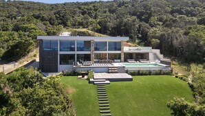 A modern house with a large glass facade, a swimming pool, and a well-maintained lawn. - Villa DEA - 380 m² villa with 6 bedrooms, panoramic sea view, beachfront, infinity pool,... (COTI CHIAVARI)