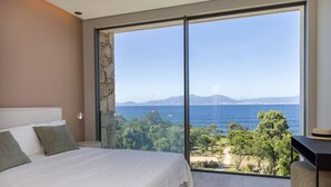 A bedroom with a large bed, a view of the sea, and a stone wall. - Villa DEA - 380 m² villa with 6 bedrooms, panoramic sea view, beachfront, infinity pool,... (COTI CHIAVARI)