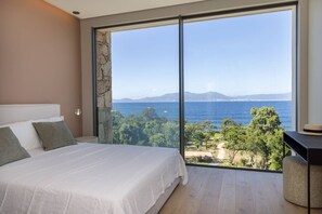 A bedroom with a large bed, a stone wall, and a view of the sea. - Villa DEA - 6 bedrooms, panoramic sea view, front of beach, swimming pool (COTI CHIAVARI)