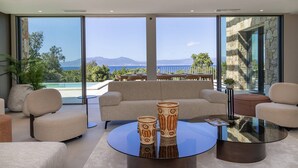 A modern living room with a sofa, two armchairs, a glass coffee table, and a view of the sea and mountains through large windows. - Villa DEA - 380 m² villa with 6 bedrooms, panoramic sea view, beachfront, infinity pool,... (COTI CHIAVARI)
