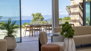 A modern living room with large windows, a sofa, a dining table with chairs, and potted plants. - Villa DEA - 380 m² villa with 6 bedrooms, panoramic sea view, beachfront, infinity pool,... (COTI CHIAVARI)
