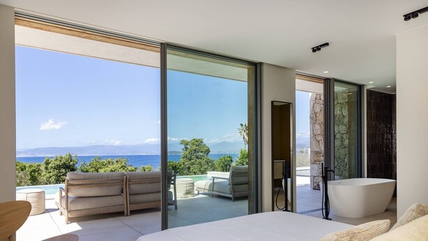 A modern bedroom with a large bed, a glass door leading to a balcony with a view of the sea and mountains, and a separate bathroom with a bathtub. - Villa DEA - 380 m² villa with 6 bedrooms, panoramic sea view, beachfront, infinity pool,... (COTI CHIAVARI)