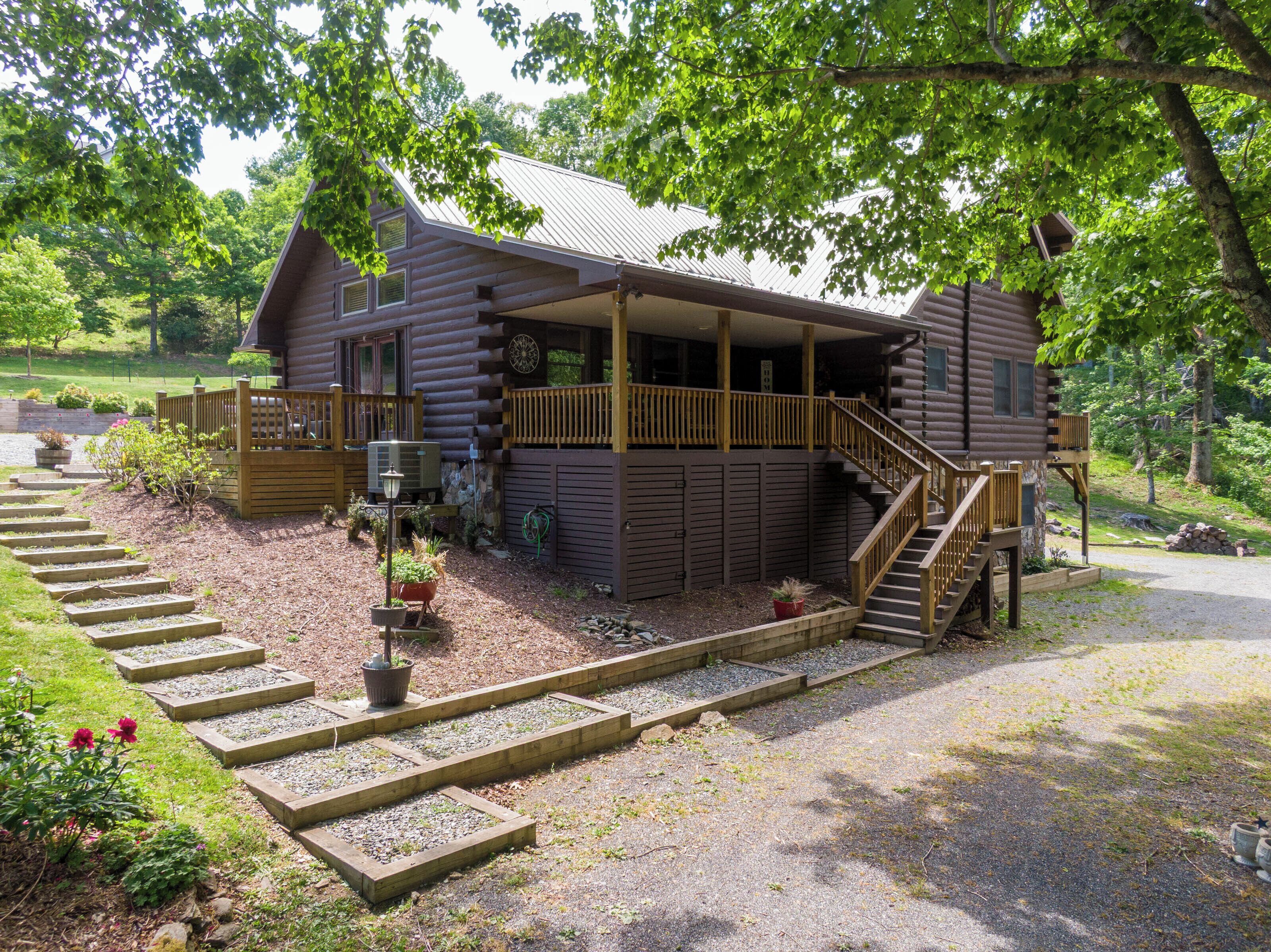 Eine Blockhütte mit Veranda, Treppe und einem Schotterweg.