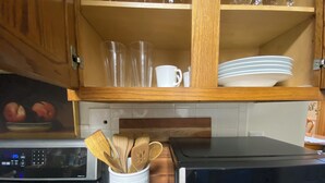 Una cocina con armarios de madera, microondas, estufa y cafetera.