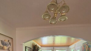 Un comedor con una mesa y sillas de madera, una araña y vistas del salón a través de un arco.