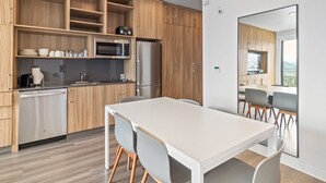 Een moderne keuken met houten kastjes, een roestvrijstalen koelkast, een magnetron en een vaatwasser.