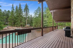 Eine Holzterrasse mit Pool, umgeben von Bäumen.