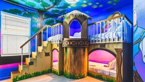 Une salle de jeux équipée d’un toboggan, d’un mur d’escalade et d’une fresque représentant une scène de forêt.
