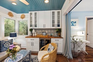 A kitchen with white cabinets, a wooden countertop, and a wicker chair. - 3 BD Sparrow Pond Cottage, Close to Beach, Community Pool, Privacy! Fun Decor! (Kiawah Island)