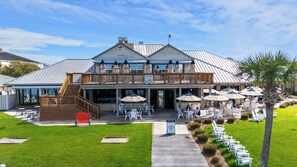 Un bâtiment à deux étages doté d’une terrasse extérieure, d’une plateforme en bois et d’une enseigne indiquant qu’il s’agit d’un café où les chiens sont les bienvenus.