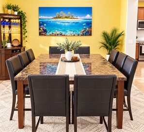 A dining area with a marble table, black leather chairs, a potted plant, and a tropical-themed painting on the wall. - Perfect 1-level, 4-bedroom, 2100 sqft house with AC in charming Avondale, AZ (Avondale)