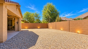 A building with a gravel patio, brick walls, and a cross symbol. - Perfect 1-level, 4-bedroom, 2100 sqft house with AC in charming Avondale, AZ (Avondale)