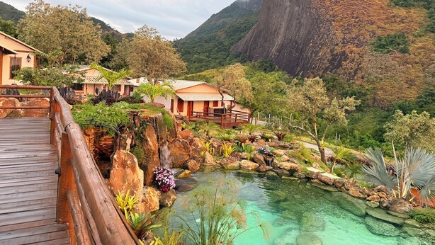 A resort with a wooden deck, a clear pool, and a mountainous backdrop. - Sitio Morro Do Balaio (Guarapari)