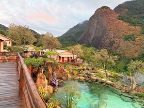 A resort with a wooden deck, a clear pool, and a mountainous backdrop. - Sitio Morro Do Balaio (Guarapari)