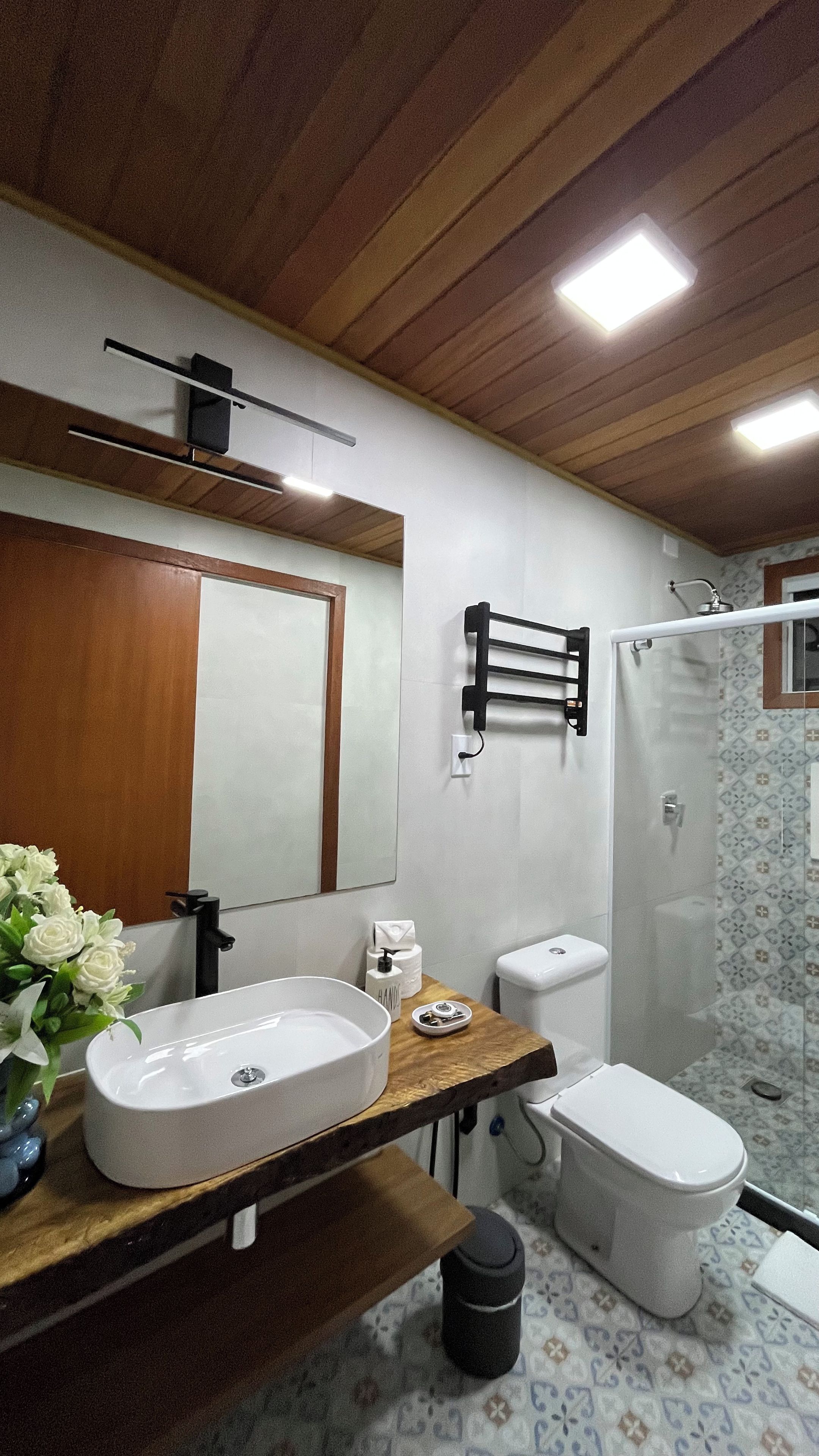 Un baño con techo de madera, un lavamanos blanco, inodoro y ducha.