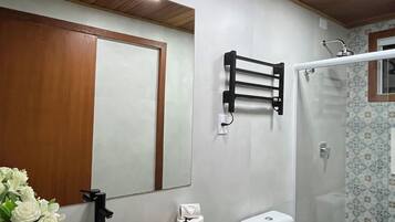 Un baño con techo de madera, un lavamanos blanco, inodoro y ducha.
