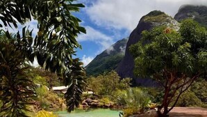 A serene outdoor area with a pathway leading to a pool, surrounded by lush greenery and a mountain backdrop. - Sitio Morro Do Balaio (Guarapari)
