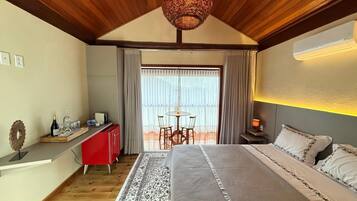A bedroom with a large bed, a desk, and a dining table.