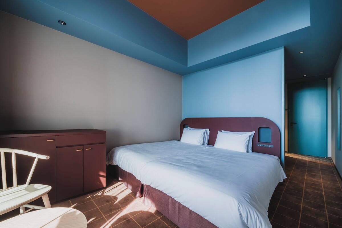 A bedroom with a bed, a wardrobe, and a chair.