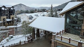 Un hotel con un área exterior cubierta de nieve, arquitectura de piedra y vistas a una montaña nevada.