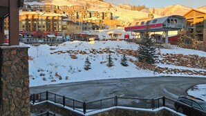 Un hotel con fachada de piedra, un telesilla y un paisaje cubierto de nieve.