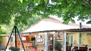 A wooden cabin with a covered patio, outdoor seating, and a swing set. - La Masure - LARROQUE (LARROQUE)
