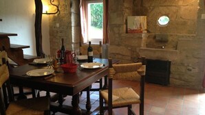 A rustic dining area with a stone wall, wooden table, and woven chairs. - La Masure - LARROQUE (LARROQUE)