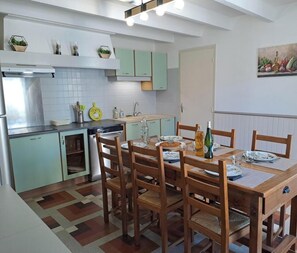 Une cuisine moderne avec des meubles de couleur vert clair, une table à manger avec des chaises et un tableau accroché au mur.