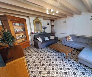 Un salon avec un canapé, une table basse, une bibliothèque, une horloge et un miroir.