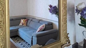 A room with a large ornate mirror, a gray sofa with a patterned pillow, and a vase with purple flowers. - Le gîte du Vigneron - LABASTIDE-DE-LEVIS (LABASTIDE-DE-LEVIS)