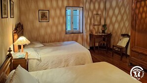 A room with two beds, a wooden ceiling, a window with curtains, a desk with a chair, and a hanging lamp. - Lou Tinalou - CASTRES (CASTRES)