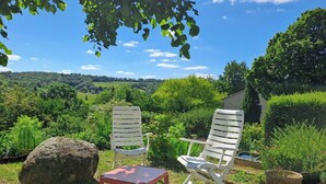 Two white chairs with slatted backs and a small table, set in a garden with a view of a green landscape and a building in the background. - Lou Tinalou - CASTRES (CASTRES)