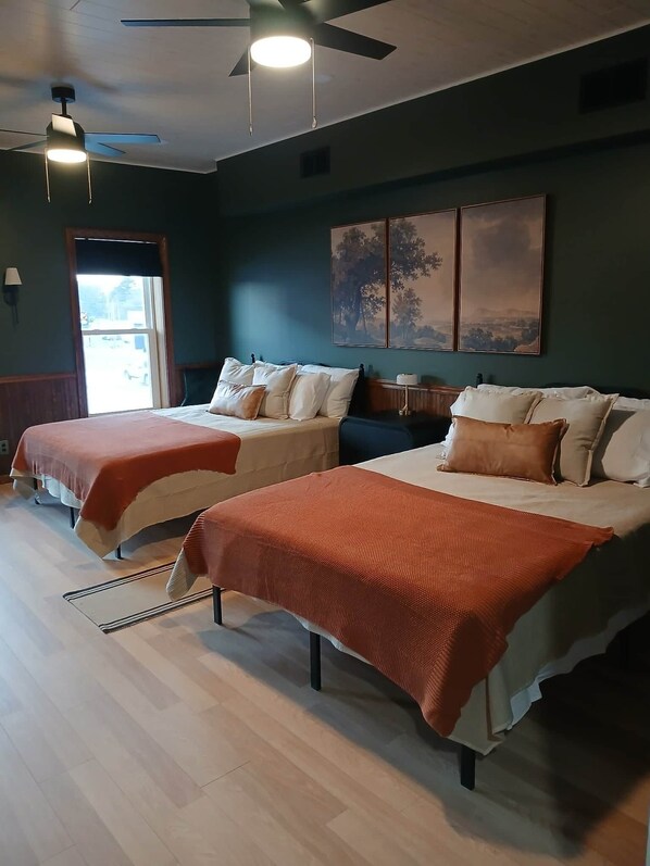 Une chambre d’hôtel avec deux lits, un ventilateur de plafond et des œuvres d’art accrochées au mur.
