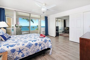 A bedroom with a bed, a ceiling fan, a view of the ocean, and a sliding door leading to a balcony. - 3 bedroom Oceanview Walk to Everything - Kamaole Beach Royale 612 (Kihei)