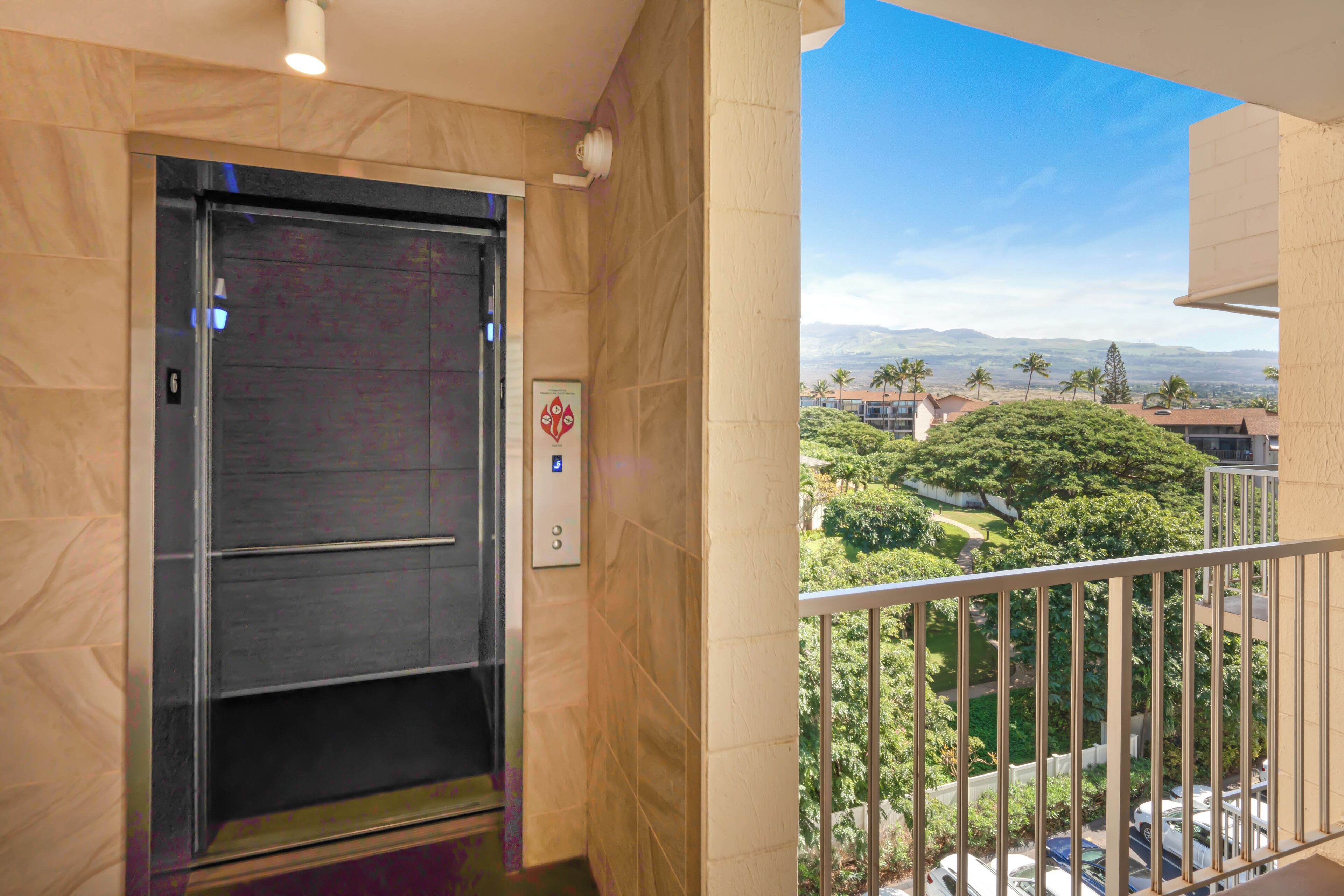 An elevator with a clear view of a lush green landscape and distant mountains through the balcony railing.