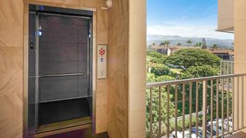 An elevator with a clear view of a lush green landscape and distant mountains through the balcony railing.