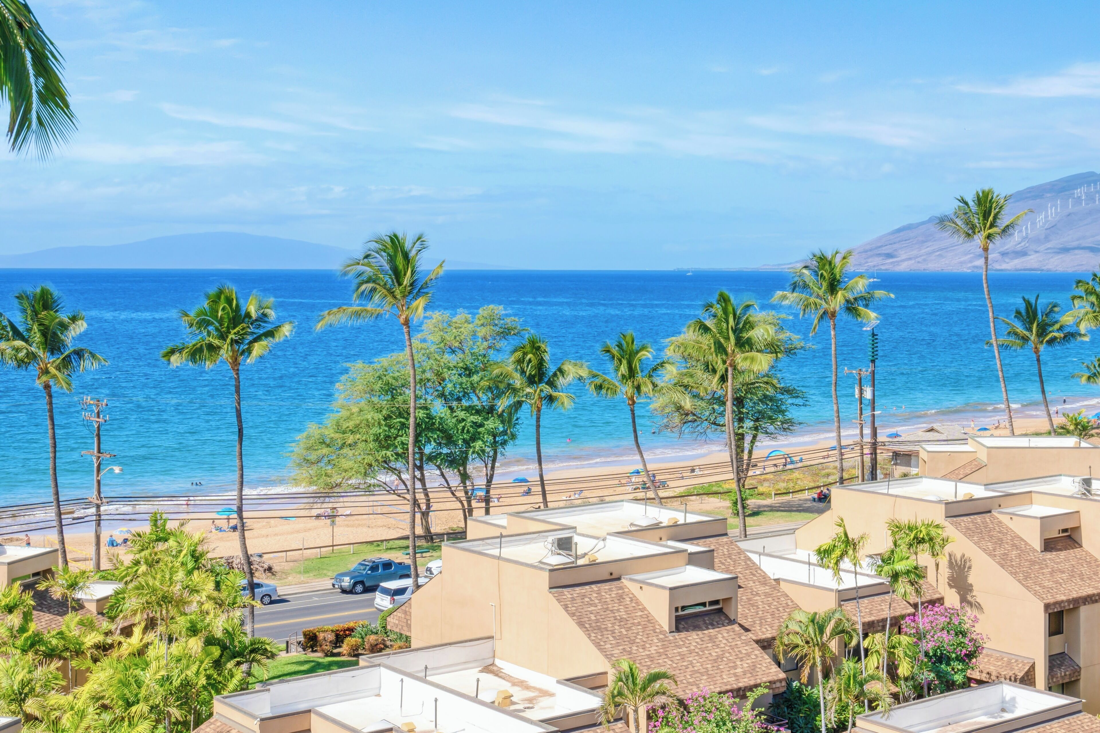 Un hotel costero con varias construcciones, palmeras y vista a la playa.
