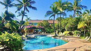 Un espace piscine avec des chaises longues et des palmiers.
