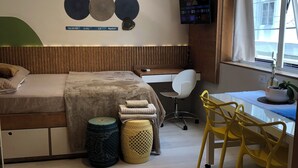 Une chambre moderne avec un lit, un bureau et une chaise, une télévision et une fenêtre avec des rideaux.