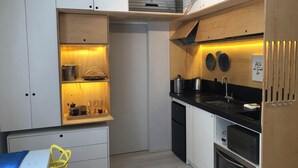 Une cuisine compacte avec des meubles blancs, un plan de travail noir et un four encastré.