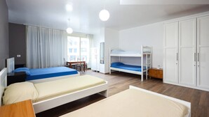 Una camera d'albergo moderna con due letti singoli, una cuccetta, una scrivania e un armadio.