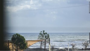 Vista sulla spiaggia con un’area sabbiosa e una struttura in legno, probabilmente una sedia o un ombrellone, sotto un cielo sereno.